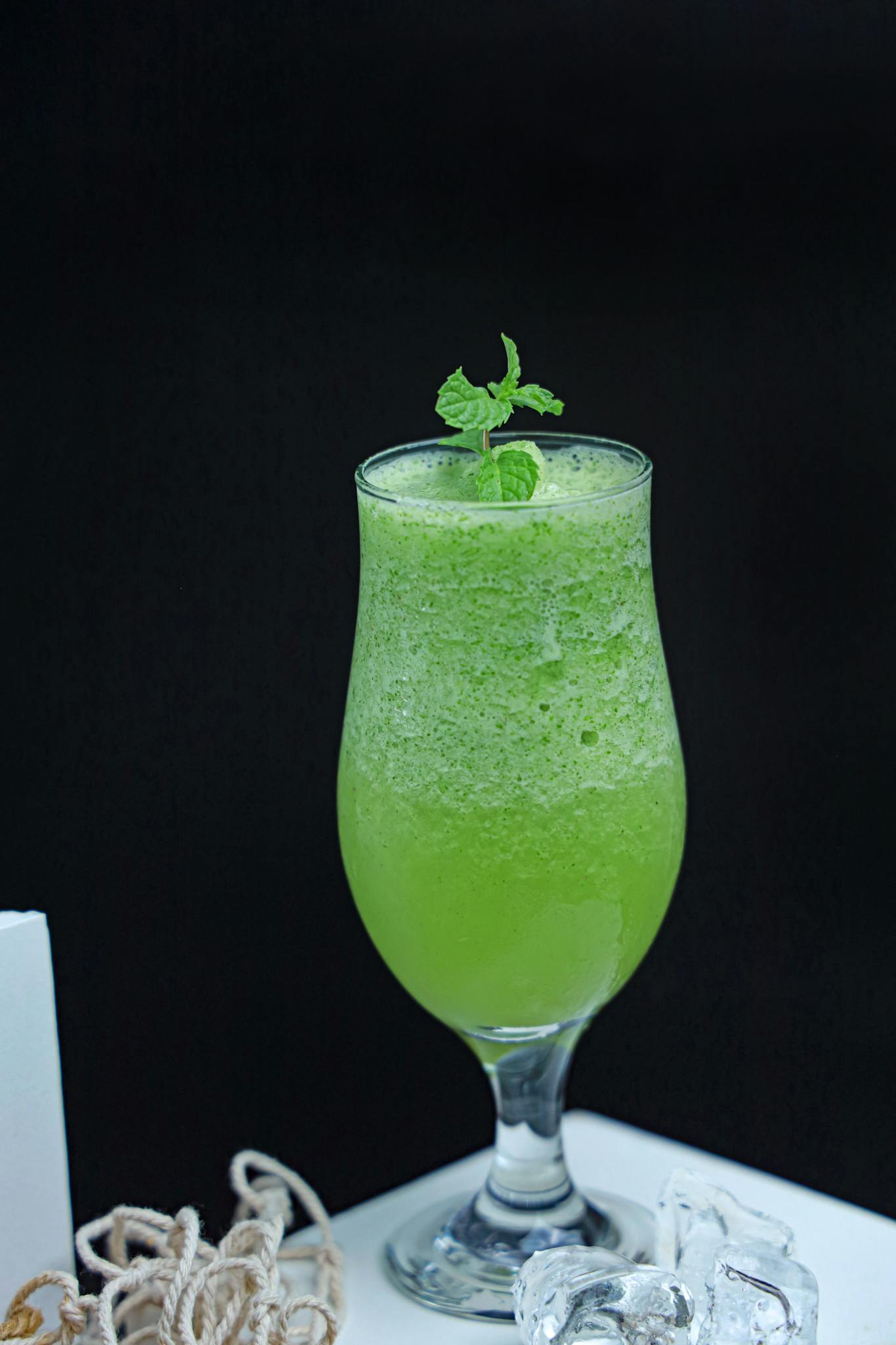 A vibrant green smoothie in a glass with fresh mint leaves, perfect for a health boost.
