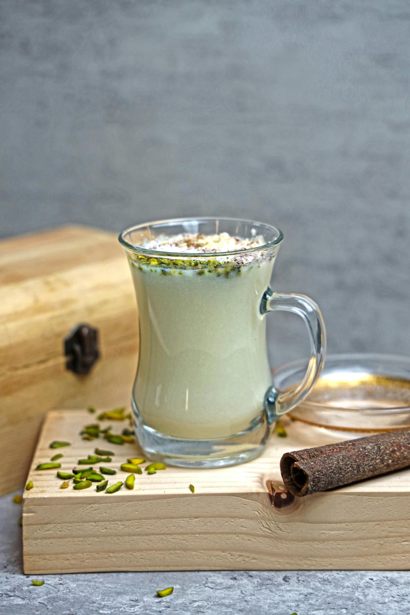 Glass of pistachio milk infused with spices on a rustic wooden board, ideal for a healthy lifestyle.